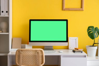 Ofiste sarı duvarın yanındaki boş ekranlı modern bilgisayar, yakın plan.