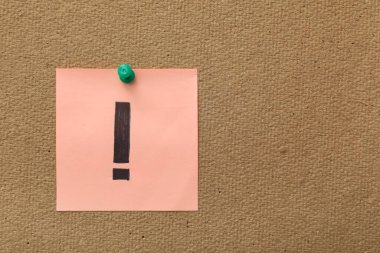 Üzerinde ünlem işareti olan pembe yapışkan bir not.