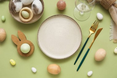 Yeşil arka planda Paskalya yumurtaları ve tüyleriyle güzel bir masa.