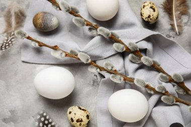 Söğüt dallı Paskalya yumurtaları, gri grunge arka planda tüyler ve peçeteler