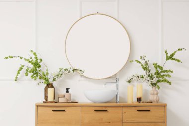 Lavabo, çiçek açan dallar ve aynalarla dolu bir banyo.