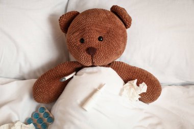 Termometresi, damlası, mendili ve hapları olan oyuncak ayı. Soğuk kavram