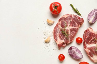Taze çiğ biftek ve beyaz arka planda farklı malzemeler.