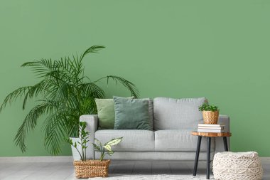 Oturma odasında kanepe, masa ve yeşil bitkiler var.