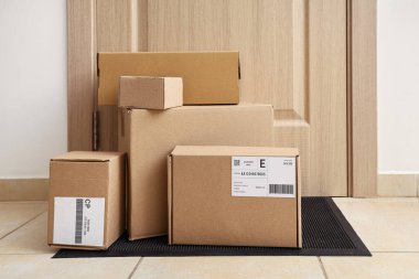 Koridordaki kapının yanındaki paspasın üzerinde bir sürü farklı paket var. Teslimat servisi