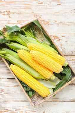 Tahta sepetin üzerinde taze mısır koçanları var.