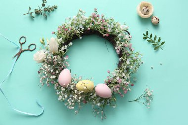 Paskalya çelengi, turkuaz arka planda çiçekler ve yumurtalar.