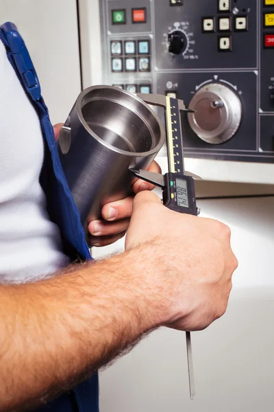 Lavoratore di fabbrica che misura il dettaglio in acciaio con pinza digitale Vernier in officina — Foto Stock