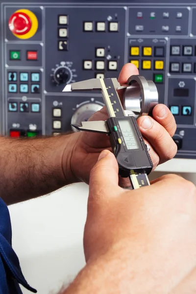 Lavoratore di fabbrica che misura il dettaglio in acciaio con pinza digitale Vernier in officina — Foto Stock
