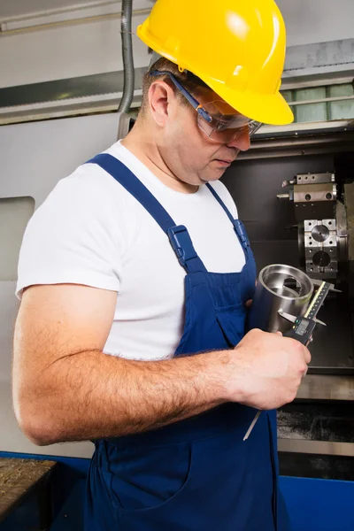 Lavoratore di fabbrica che misura il dettaglio in acciaio con pinza digitale Vernier in officina — Foto Stock
