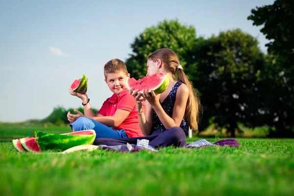 Jongen en een meisje watermeloen te eten op een zonnige dag — Stockfoto