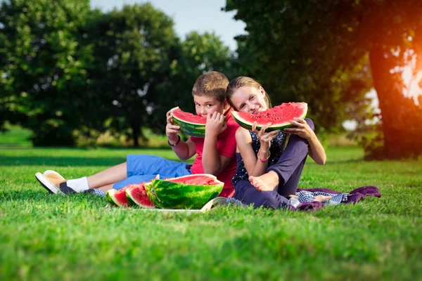 Jongen en een meisje watermeloen te eten op een zonnige dag — Stockfoto