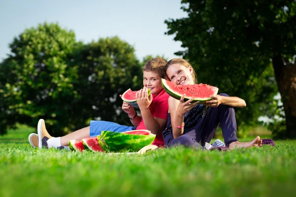 Jongen en een meisje watermeloen te eten op een zonnige dag — Stockfoto