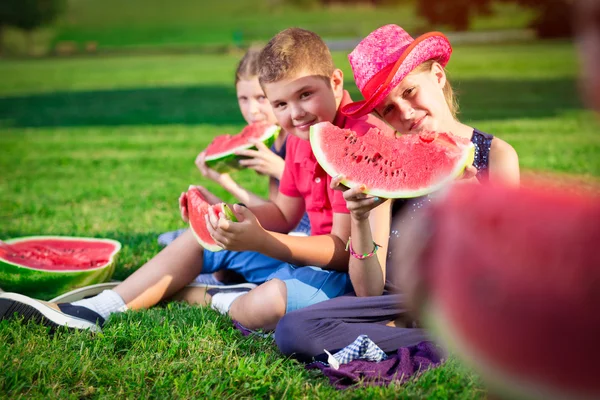 晴れた日にスイカを食べているかわいい子供たち — ストック写真