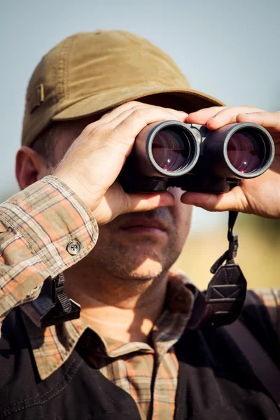 Man jägare med hagelgevär tittar genom kikaren i skogen — Stockfoto