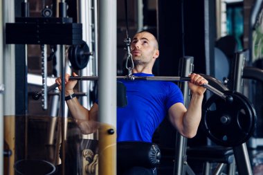 Spor salonunda makine üzerinde egzersiz yapan formda bir adam..