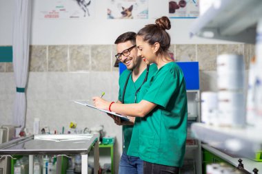 Veteriner doktor elinde dosya, veteriner kliniğinde not alıyor.