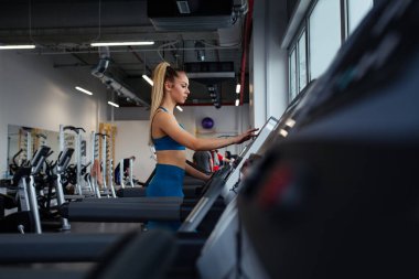 Kadın hızı koşu bandına ayarlıyor..