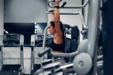 spor salonunda bir makinede kol egzersizleri yapıyor kadın