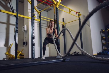 Savaş halatları seansı. Çekici genç fit ve formda sporcu kadın antrenmanı.