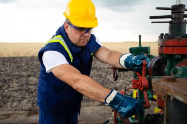 Petrol işçisi petrol boru hattının vanasını açıyor. Petrol ve Gaz Sanayii.