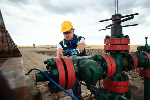 石油労働者は石油パイプラインでバルブを回している ガス産業 ロイヤリティフリーのストック画像