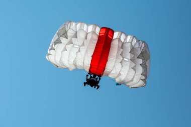 Gökyüzünde paraşüt. Paraşütçü mavi gökyüzünde paraşütle atlıyor..
