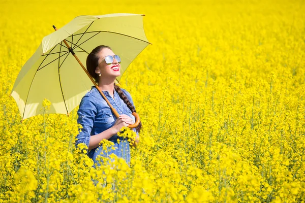 Young woman with an umbrella in canola field — Stock Photo, Image