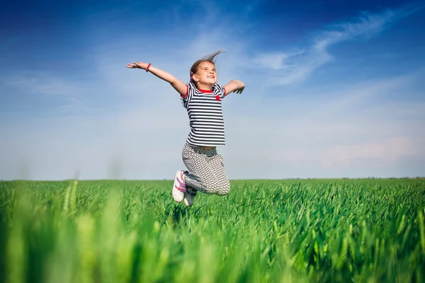 Menina sorridente feliz pulando no campo de trigo — Fotografia de Stock