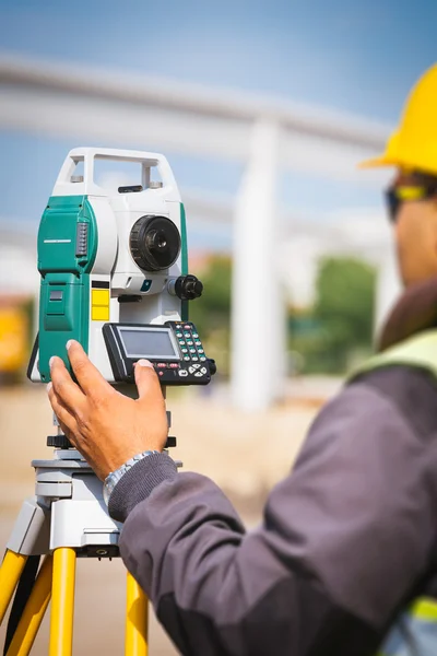 Trabalhador engenheiro de topografia fazendo medições com equipamentos de ferramentas de teodolita no canteiro de obras — Fotografia de Stock