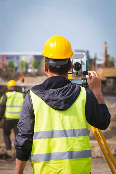 Trabalhador engenheiro de topografia fazendo medições com equipamentos de ferramentas de teodolita no canteiro de obras — Fotografia de Stock