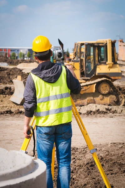 Arazi mühendisi işçi teodolit aracı ekipmanları inşaat sahasında ile ölçüm yapmak — Stok fotoğraf