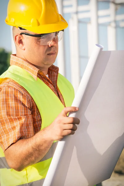 Construction manager controlling building site with plan — Stock Photo, Image