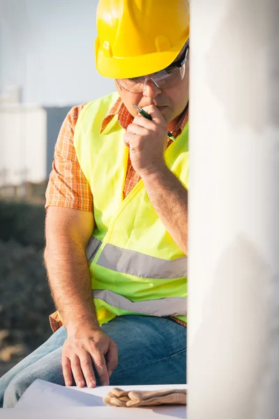 Construction manager controlling building site with plan — Stock Photo, Image