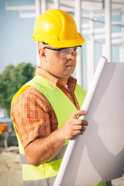 Construction manager controlling building site with plan — Stock Photo, Image