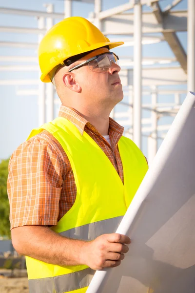 Construction manager controlling building site with plan — Stock Photo, Image