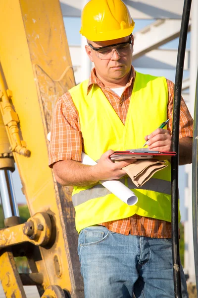 Construction manager controlling building site with plan — Stock Photo, Image