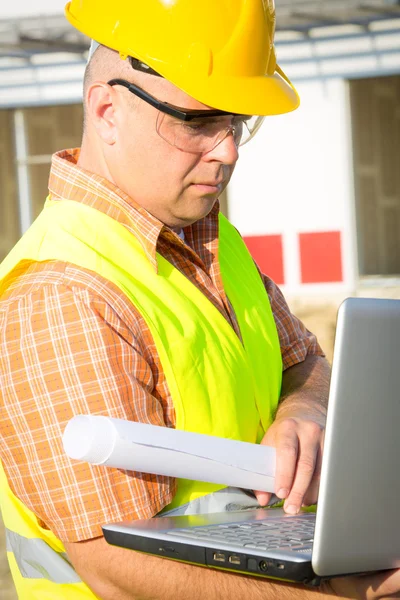 Construction manager controlling building site with plan — Stock Photo, Image