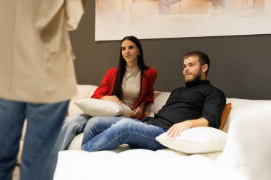 Mobilya mağazasında kanepeleri karşılaştıran, ev kararları veren genç bir çift.
