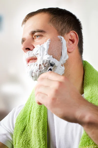 Handsome young man is shaving his face — Stock Photo, Image