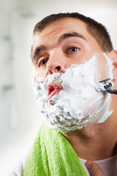 Handsome young man is shaving his face — Stock Photo, Image