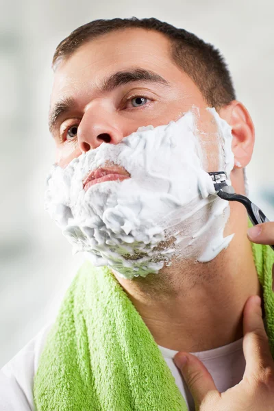 Красивый молодой человек бреет лицо. — стоковое фото