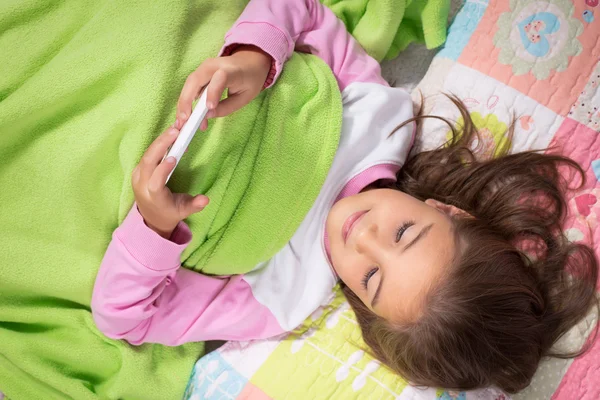 Een klein meisje liggend op het bed — Stockfoto