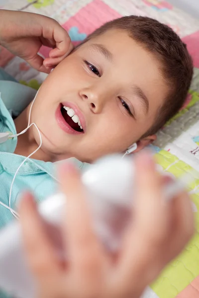 Gelukkige jongen luisteren naar muziek in de slaapkamer — Stockfoto