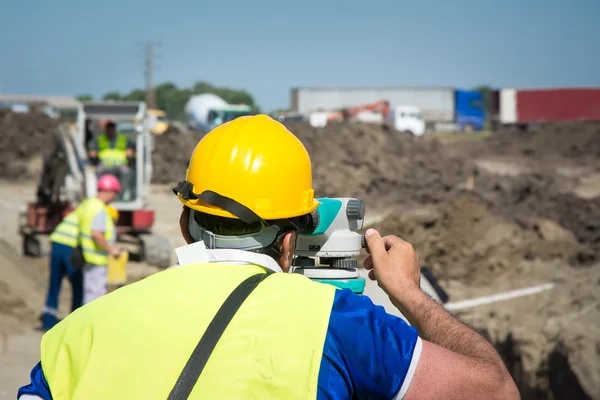 Engenheiros de vistoria que trabalham com teodolite em canteiros de obras rodoviárias — Fotografia de Stock