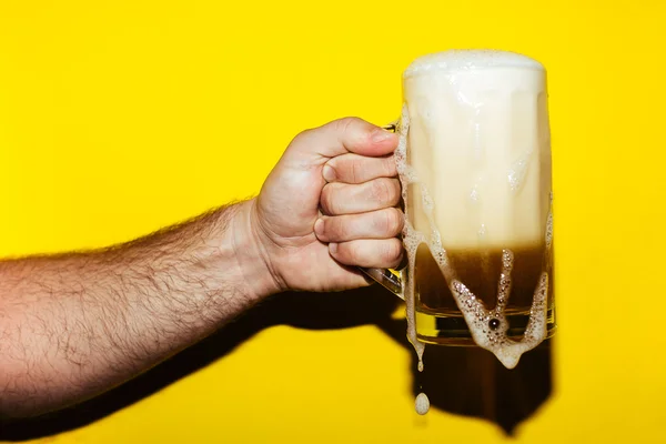 Tazza mano di birra su sfondo giallo — Foto Stock