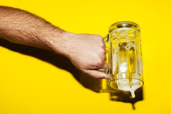 Hand houden mok van bier op gele achtergrond — Stockfoto