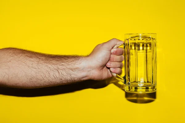 Ruce drží sklenku piva na žlutém podkladu — Stock fotografie