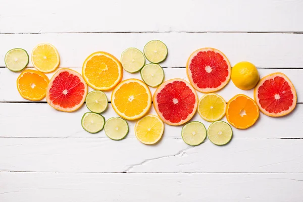 Toranja limão, tangerina, laranja e rosa sobre madeira branca — Fotografia de Stock