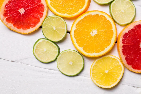 Toranja limão, tangerina, laranja e rosa sobre madeira branca — Fotografia de Stock